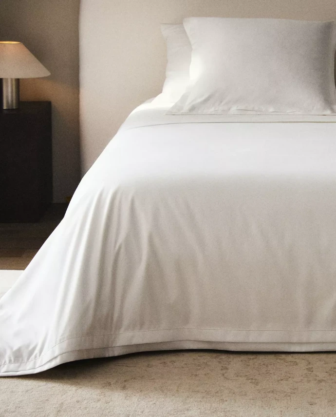 Lit dressé avec draps et housse de couette blancs